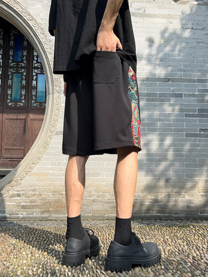 Back view of black woven patchwork shorts showing pocket and side pattern