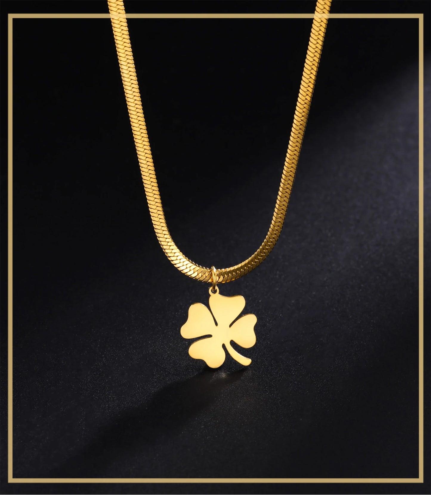 Close-up of gold clover cross pendant with snake chain on black surface