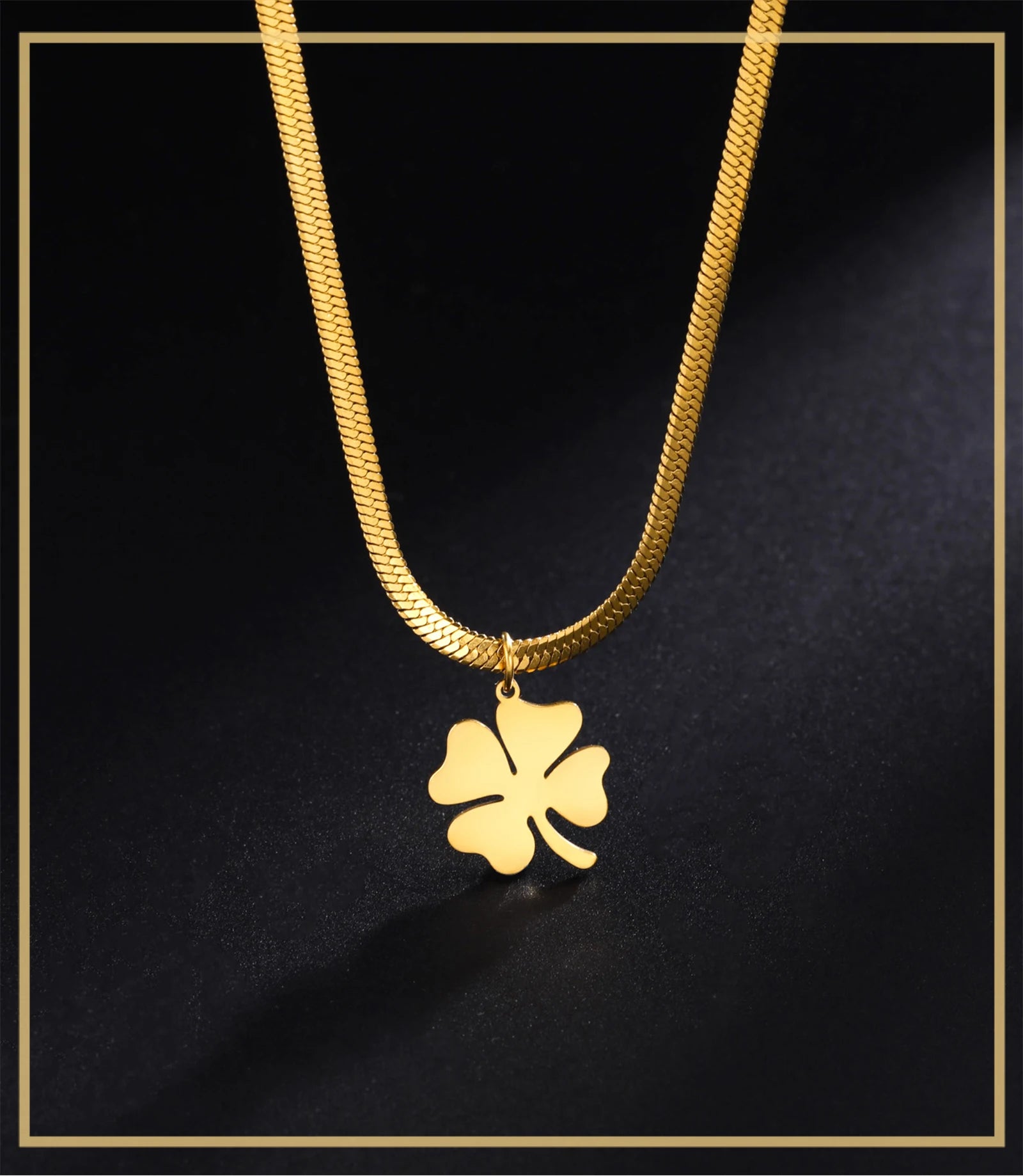 Close-up of gold clover cross pendant with snake chain on black surface