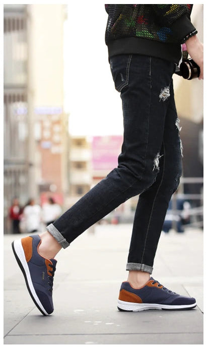 Close-up of navy and orange sneakers being tied on foot, side view