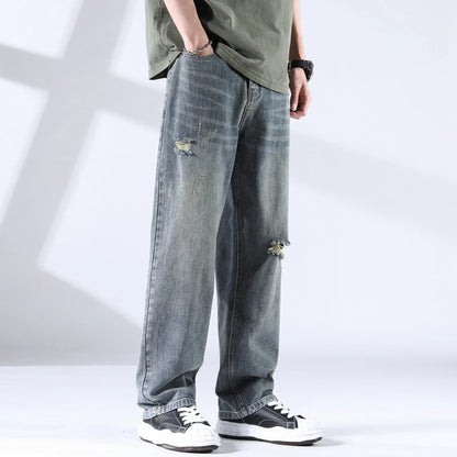 Close side-front view of storm grey-blue distressed jeans with soft fading and ripped knee