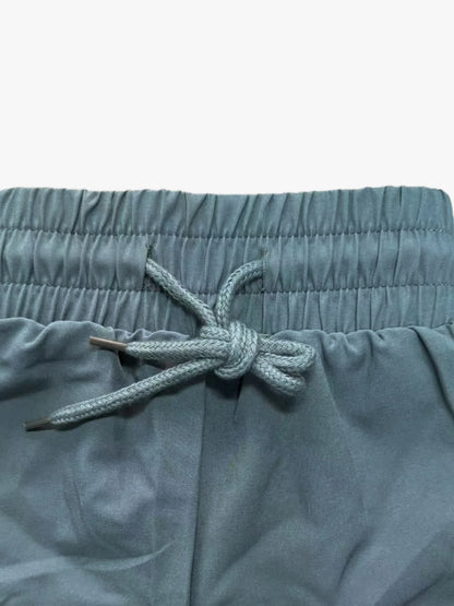 Detailed close-up of teal workout shorts waistband and braided drawstring tie, front view