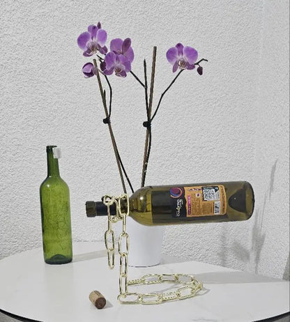 Gold chain wine holder with floral-decorated bottle and purple flowers