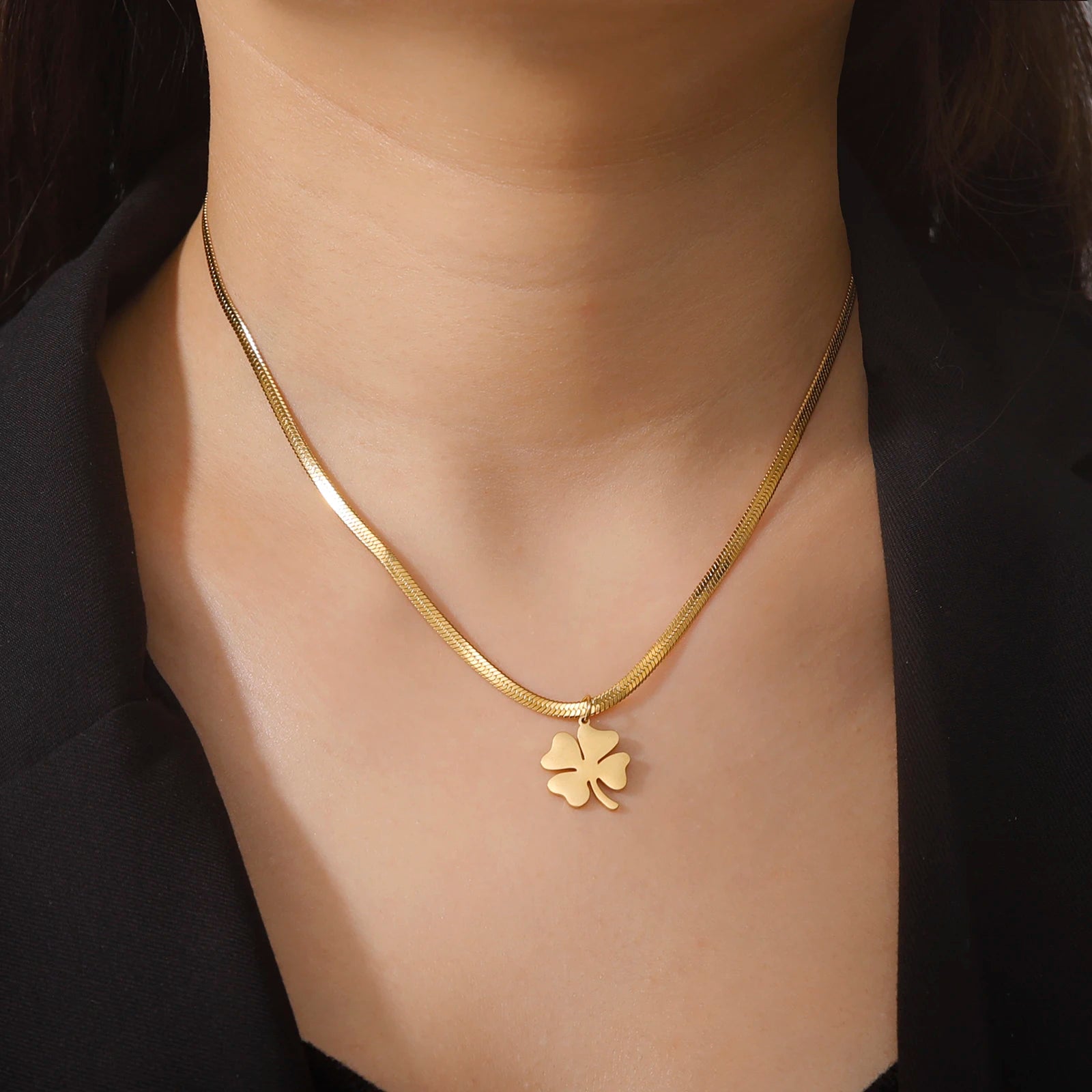 Gold clover necklace worn with black outfit, centered close-up