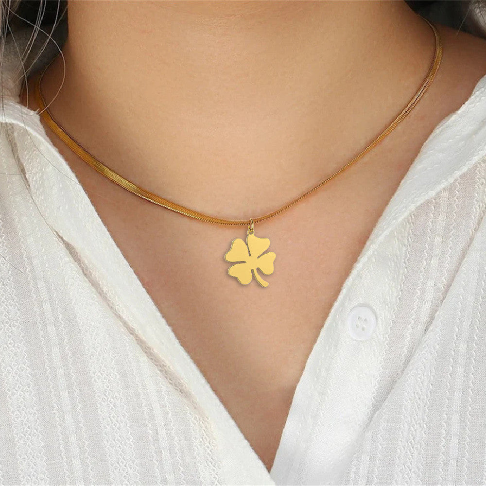 Gold clover pendant necklace worn with white blouse, natural light