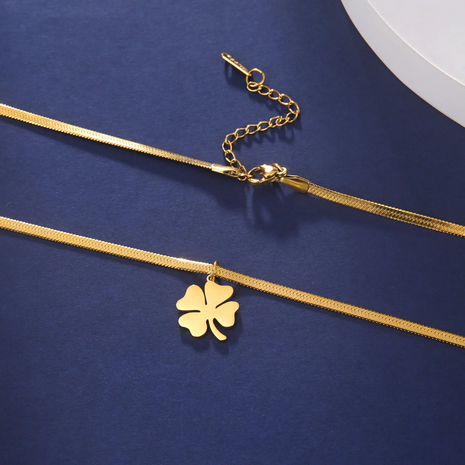Gold stainless steel clover necklace with clasp and extension chain on blue background