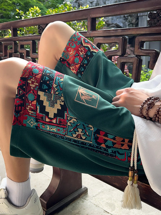 Green shorts with embroidered ethnic panel, seated close-up view