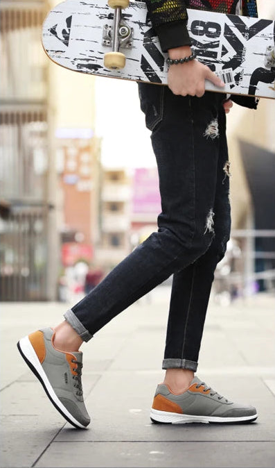 Grey and orange sneakers with light blue jeans in walking motion, side view