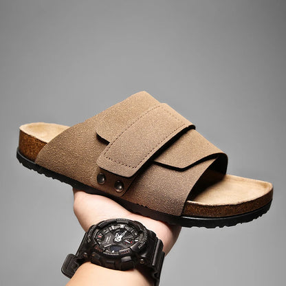 Light taupe suede slide sandal for men with cork footbed, held for side view