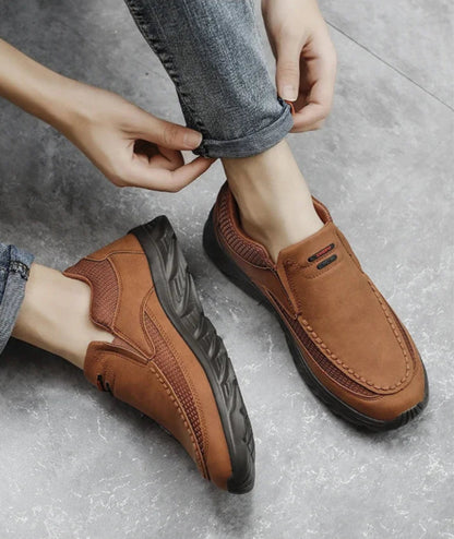 Man adjusting jeans while wearing brown slip-on leather loafers