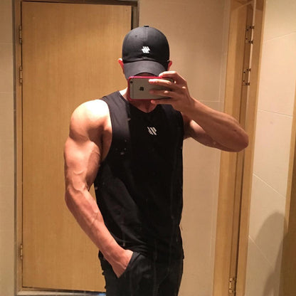 Man wearing black mesh tank top in bathroom mirror selfie with door background
