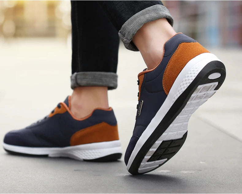 Navy and orange sneakers with legs mid-stride on pavement