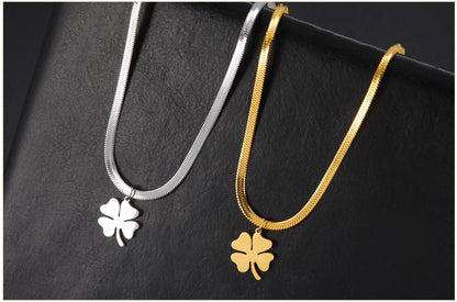 Pair of gold and silver clover necklaces displayed on textured leather surface