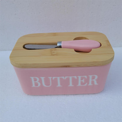 Pink ceramic butter dish with bamboo lid and white spreader, side view