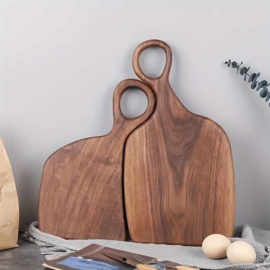 Set of two walnut cutting boards with loop handles standing upright on counter