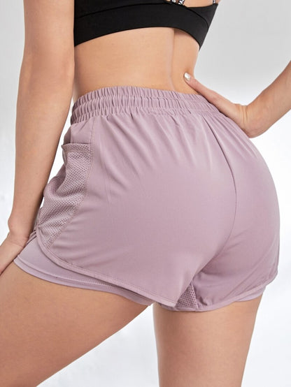 Side angle of pink dual-layer athletic shorts featuring deep mesh pocket and curved hem