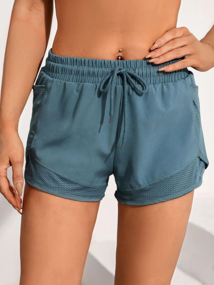 Side angle of teal dual-layer athletic shorts featuring deep mesh pocket and curved hem