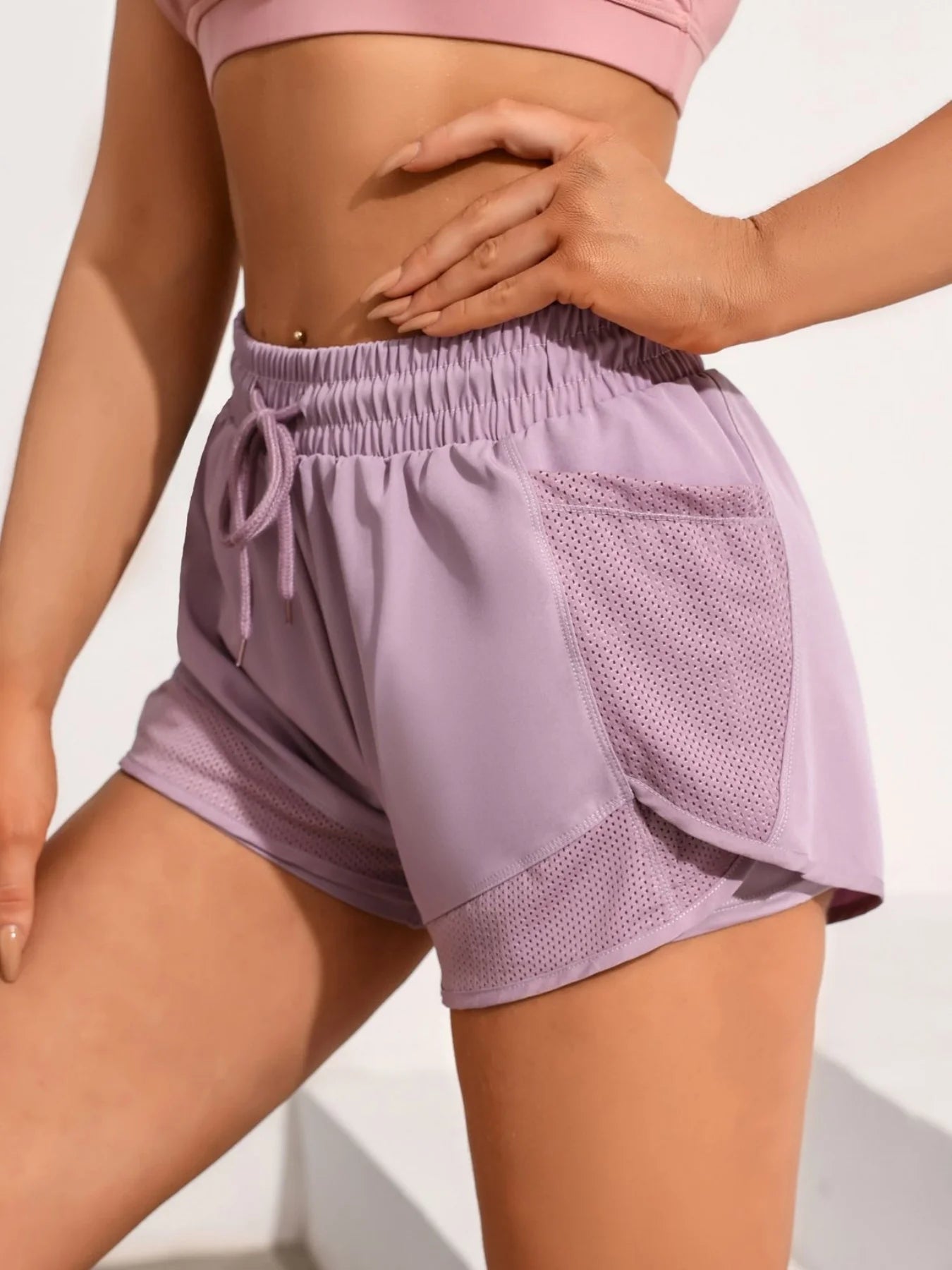 Side view of lavender workout shorts showing mesh pocket and layered design in natural light