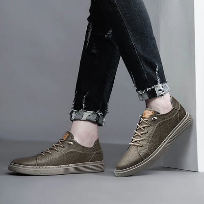 Side view of taupe leather sneakers in casual outfit, one foot on wall