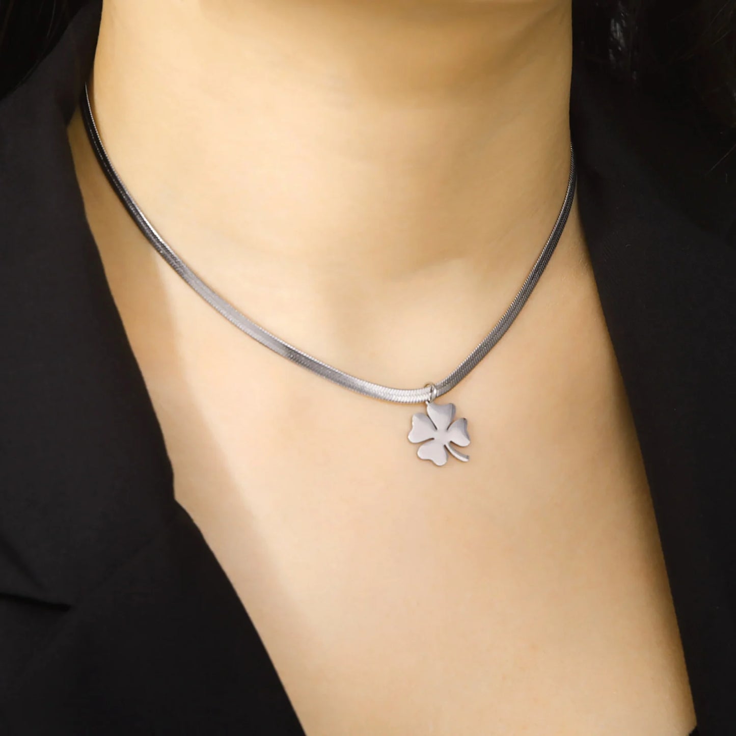 Silver clover necklace worn with blazer, angled view