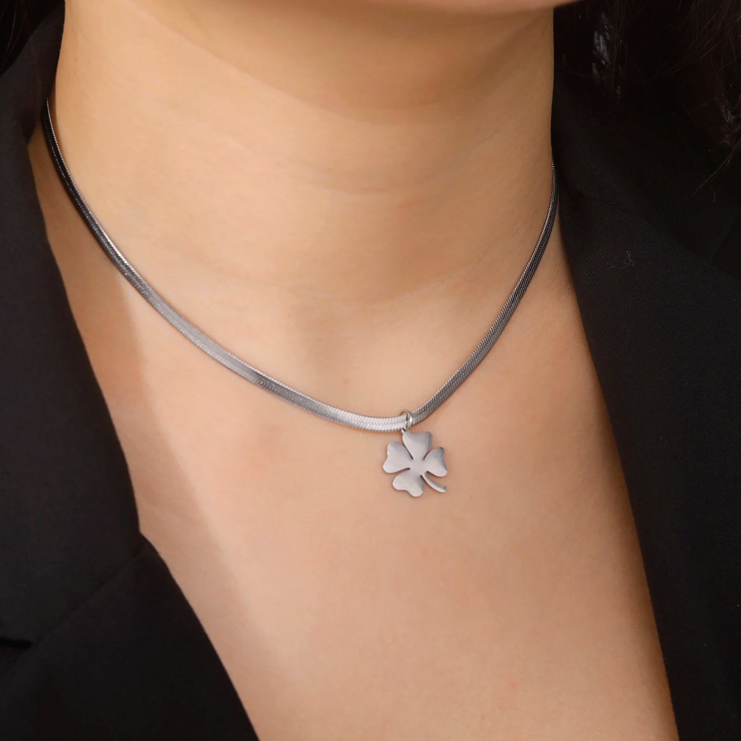 Silver clover pendant necklace on model, angled neck view with black clothing
