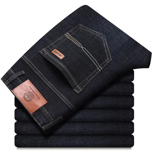 Stack of folded black men's jeans with contrast stitching and leather label, back pocket top view