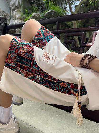 White ethnic shorts with colorful woven side panels, seated view